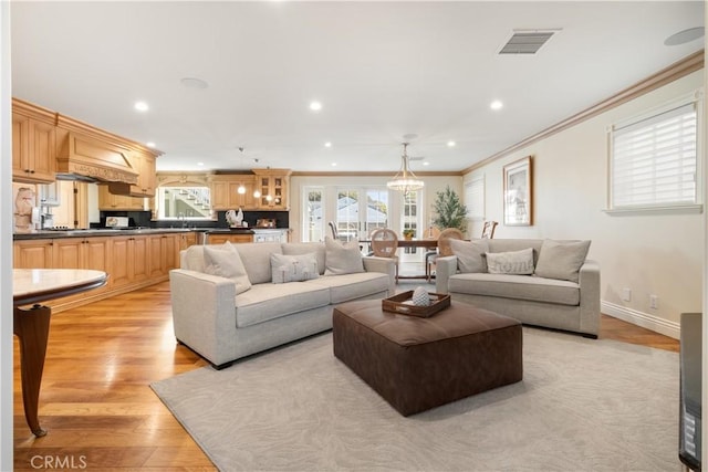 living area with visible vents, recessed lighting, light wood-style floors, crown molding, and baseboards