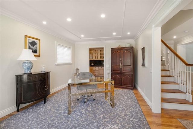 home office with crown molding, light wood-style floors, and baseboards