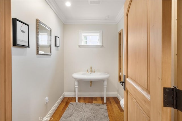 bathroom with toilet, wood finished floors, baseboards, and ornamental molding