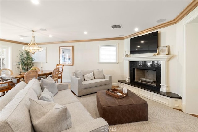 living area with visible vents, baseboards, ornamental molding, a fireplace, and an inviting chandelier