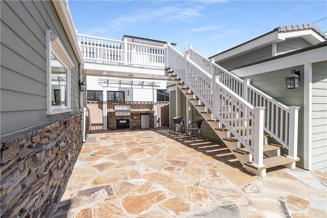 view of patio / terrace with a grill, stairs, and exterior kitchen