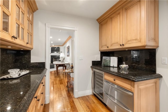 kitchen featuring light wood-style flooring, tasteful backsplash, wine cooler, glass insert cabinets, and baseboards