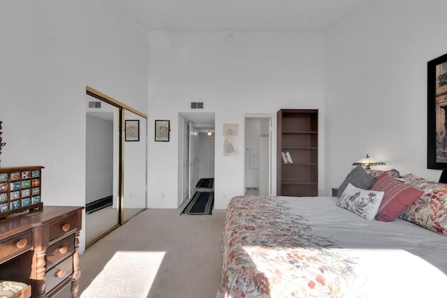 carpeted bedroom featuring a closet, visible vents, and a towering ceiling