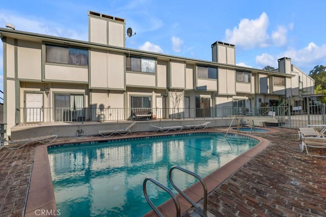 community pool featuring a patio and fence