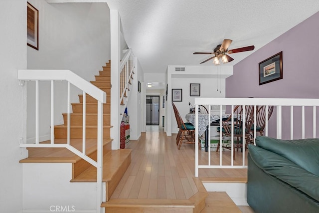 foyer with visible vents, ceiling fan, stairway, hardwood / wood-style flooring, and a textured ceiling