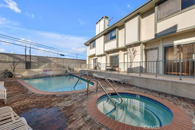 community pool featuring a patio area, fence, and a hot tub