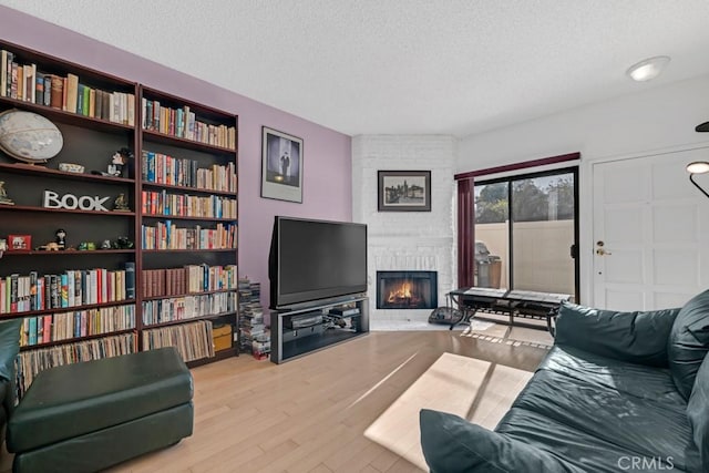 living room with a fireplace, a textured ceiling, and wood finished floors