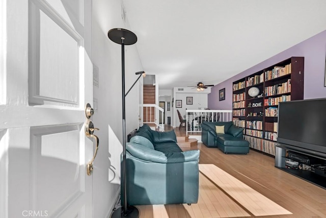 living area featuring ceiling fan, stairway, and wood finished floors