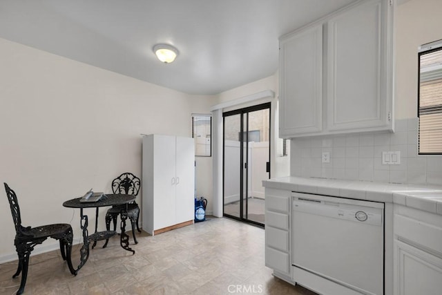 kitchen featuring tasteful backsplash, baseboards, tile countertops, dishwasher, and white cabinets