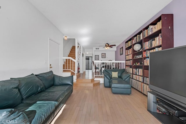 living area featuring ceiling fan, stairway, and light wood-style flooring