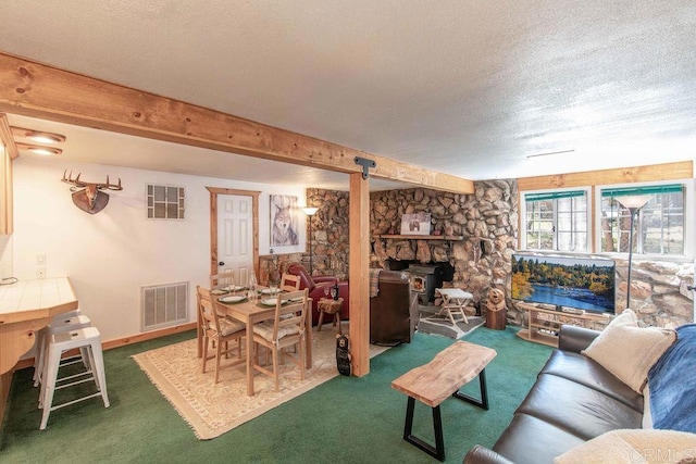 carpeted living area with beam ceiling, a wood stove, visible vents, and a textured ceiling