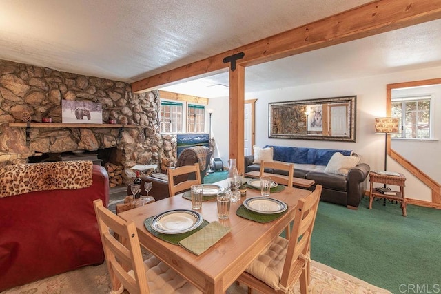 carpeted dining space with beam ceiling, a fireplace, baseboards, and a textured ceiling