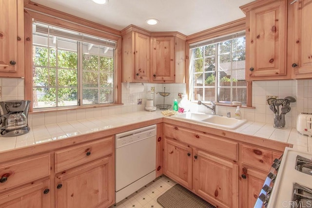 kitchen featuring a sink, tasteful backsplash, tile countertops, light floors, and dishwasher