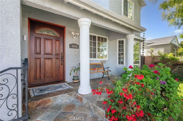 view of exterior entry with stucco siding and covered porch