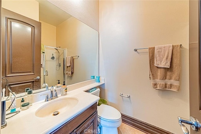 bathroom with a stall shower, toilet, vanity, and baseboards