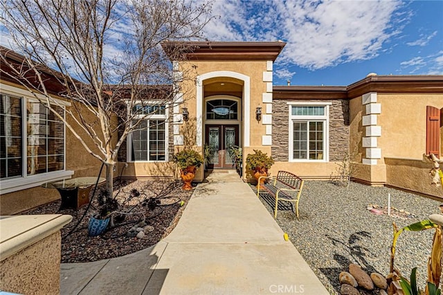 doorway to property featuring stone siding, stucco siding, and french doors