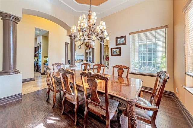 dining room featuring arched walkways, baseboards, and decorative columns