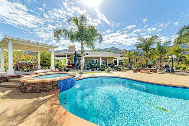 view of pool with a pool with connected hot tub, a fire pit, and a patio