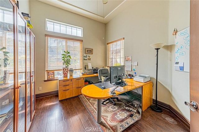 home office with dark wood-style floors, baseboards, and a towering ceiling