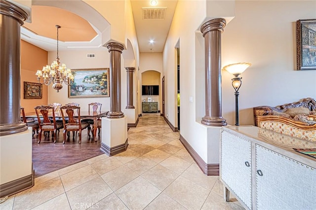 hallway featuring light tile patterned floors, visible vents, arched walkways, and ornate columns