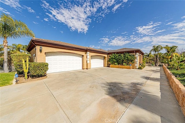 view of front of property with concrete driveway, an attached garage, and stucco siding