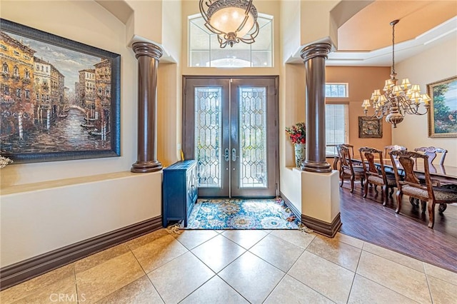 entryway with light tile patterned flooring, a notable chandelier, french doors, and decorative columns