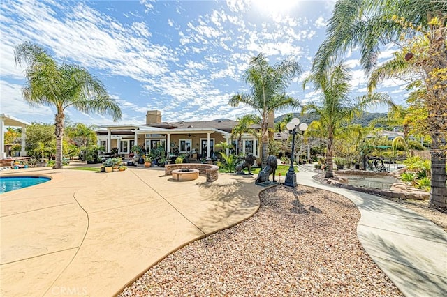 exterior space featuring a swimming pool, a patio, and an outdoor fire pit