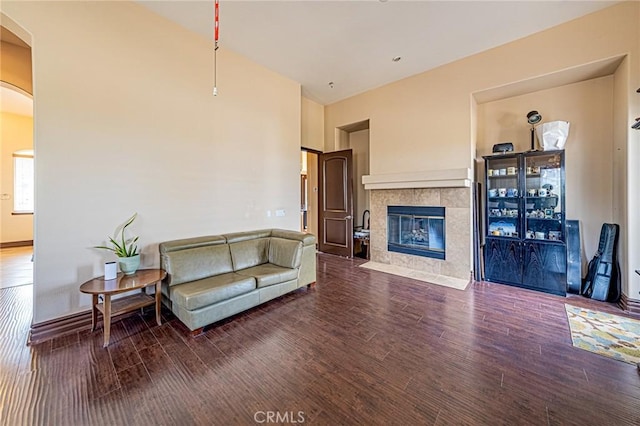 living room featuring a tiled fireplace, wood finished floors, and arched walkways