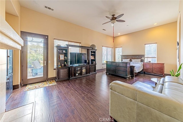 living room featuring visible vents, baseboards, dark wood-type flooring, and a ceiling fan