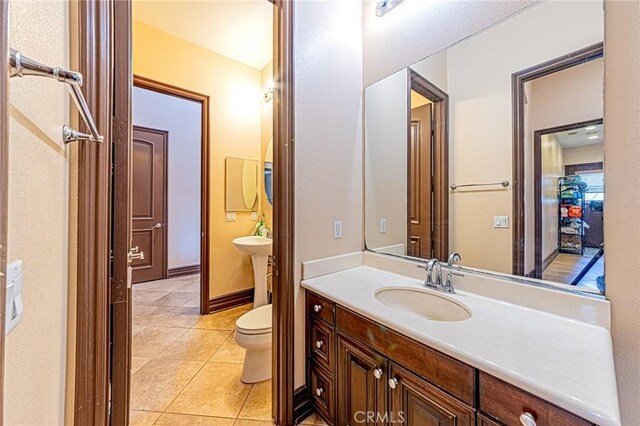 bathroom featuring tile patterned flooring, toilet, baseboards, and a sink