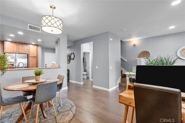 dining area featuring visible vents, wood finished floors, recessed lighting, baseboards, and stairs