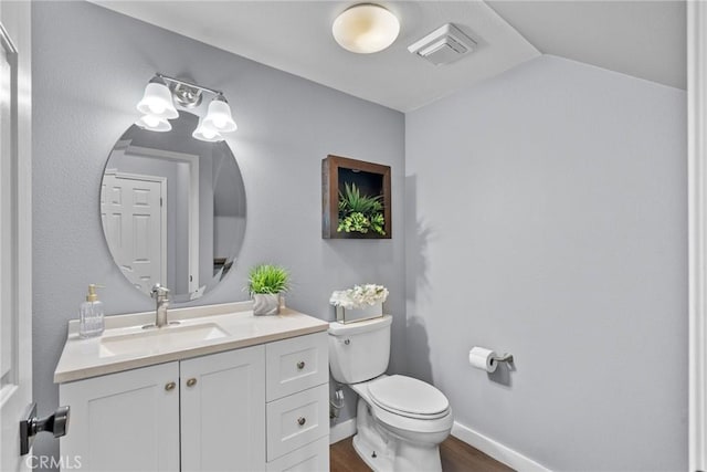 half bathroom with visible vents, toilet, wood finished floors, baseboards, and vanity