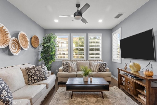 living room with visible vents, baseboards, wood finished floors, and a ceiling fan