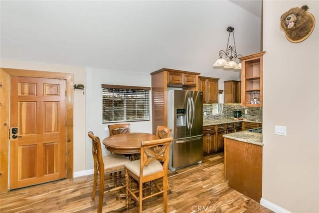 kitchen with backsplash, brown cabinets, light wood-style flooring, and stainless steel fridge with ice dispenser