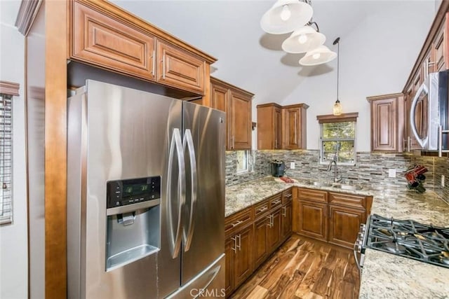 kitchen with light stone counters, decorative backsplash, appliances with stainless steel finishes, and brown cabinetry