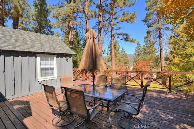 wooden deck featuring outdoor dining area and an outdoor structure