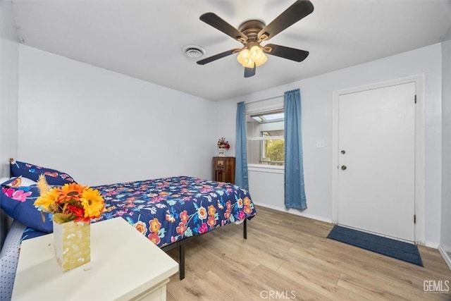 bedroom featuring light wood finished floors, visible vents, baseboards, and a ceiling fan