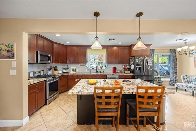 kitchen with a sink, stainless steel appliances, light stone countertops, and decorative backsplash