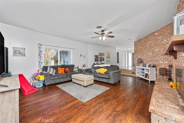 living room with visible vents, brick wall, a ceiling fan, and wood finished floors