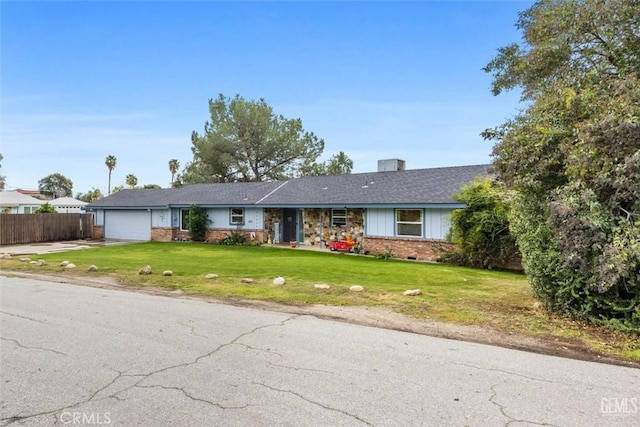 ranch-style home featuring a front lawn, fence, concrete driveway, an attached garage, and brick siding