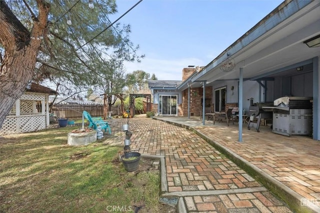 view of yard with a patio, fence, and an outdoor fire pit