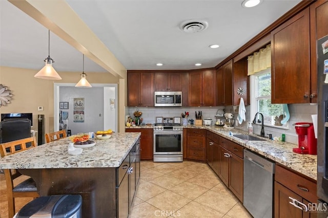 kitchen featuring light stone counters, visible vents, a sink, stainless steel appliances, and tasteful backsplash