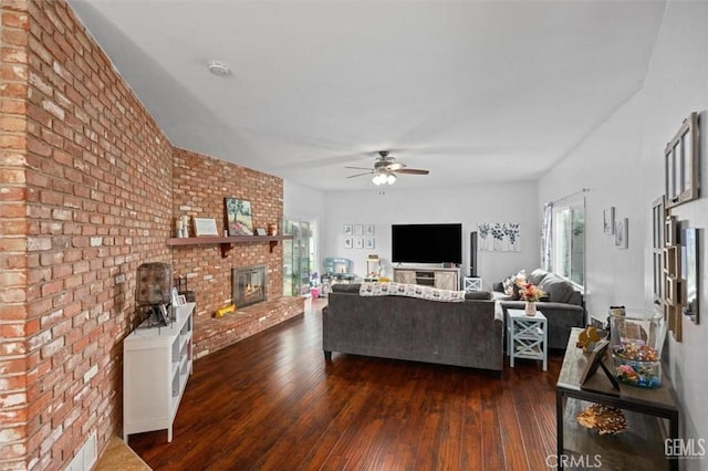 living room with a ceiling fan, dark wood-type flooring, a fireplace, and brick wall