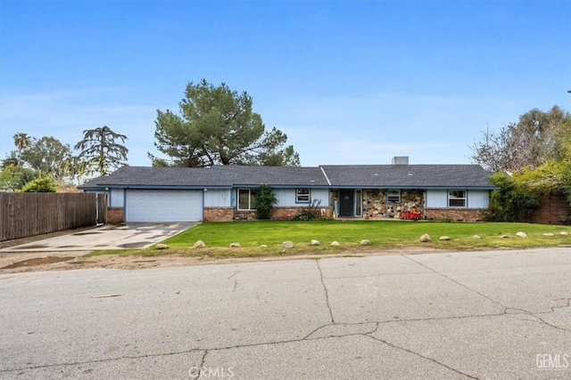 ranch-style home featuring a front yard, fence, driveway, an attached garage, and brick siding