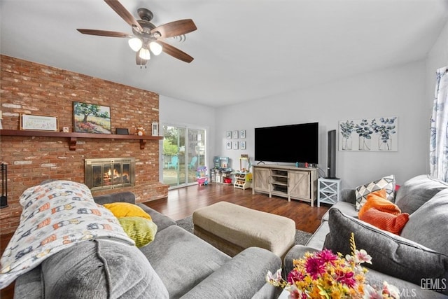 living area with ceiling fan, a brick fireplace, wood finished floors, and brick wall