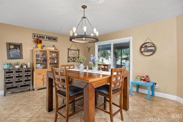 dining area with light tile patterned floors, baseboards, and a notable chandelier