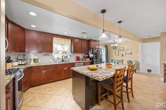 kitchen with a sink, tasteful backsplash, appliances with stainless steel finishes, and light tile patterned floors