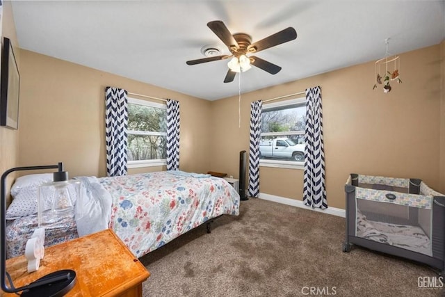 carpeted bedroom with multiple windows, a ceiling fan, and baseboards