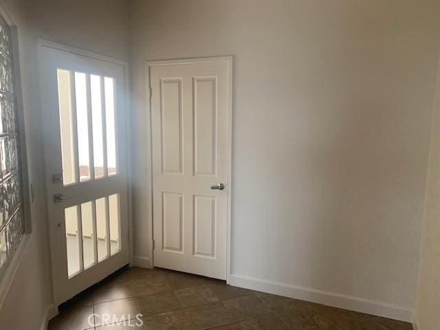 entryway with dark tile patterned floors, plenty of natural light, and baseboards