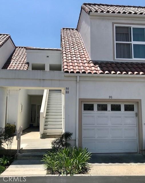 view of front of house featuring driveway, a tile roof, and a garage